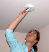 A woman changing the batteries in a smoke detector